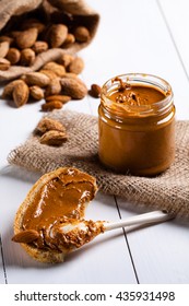 Homemade Almond Butter In A Glass Jar And Sandwich Smeared With A Ceramic Spoon.