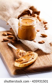 Homemade Almond Butter In A Glass Jar And Sandwich Smeared With A Ceramic Spoon.