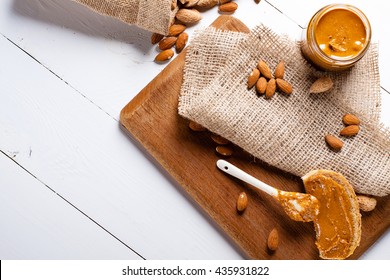 Homemade Almond Butter In A Glass Jar And Sandwich Smeared With A Ceramic Spoon.