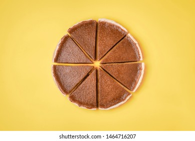Homemade american pie. Flat lay of a pumpkin pie, cut in slices, on a yellow background. Minimal image of Thanksgiving dessert. Sliced pumpkin cake.
