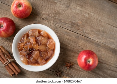 Homemade Apple Chutney (apple jam, marmalade, chunky sauce) with cinnamon, anise and apples on wooden background, copy space. Traditional autumn apple jam.