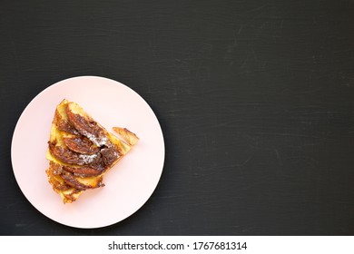 Homemade Apple Dutch Pannekoek Pancake On A Pink Plate On A Black Background, Top View. Flat Lay, Overhead, From Above. Space For Text.