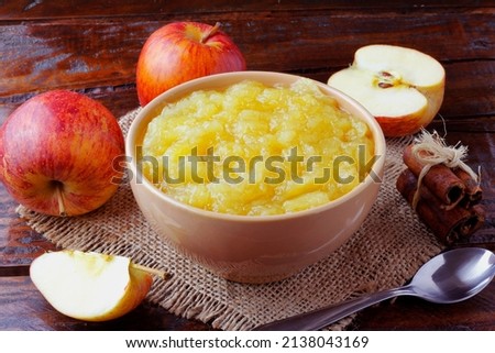 homemade apple sauce or apple puree in ceramic bowl over rustic wooden table. top view
