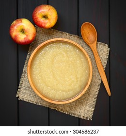 Homemade Apple Sauce In Wooden Bowl With Wooden Spoon And Fresh Apples On The Side, Photographed Overhead On Dark Wood With Natural Light