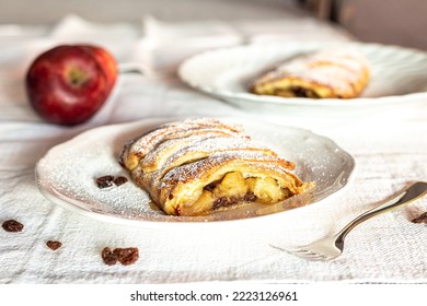Homemade apple strudel with puff pastry, cinnamon, sultanas, pine nuts on white plate. Christmas apple strudel.