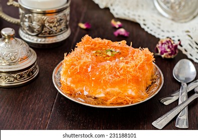  Homemade arabian traditional sweets Kunafa with pistachio and honey syrup on dark wooden background