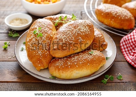 Homemade baked pies or patties stuffed with cabbage on wooden background