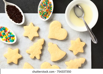 Homemade Baked Sugar Cookies For Christmas With Icing And Sprinkles On The Side, Photographed Overhead On Slate