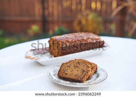 Homemade banana bread with pecan nuts served as a delicious and tasty breakfast or snack outside in the garden during summer sunny morning. Ideal dish for modern healthy, lowcarb and balanced diet.