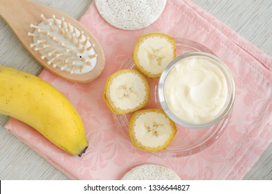 Homemade Banana Face And Hair Mask (cream) In The Small Glass Jar And Wooden Hair Brush. DIY Beauty Treatments And Spa. Top View, Copy Space. 
