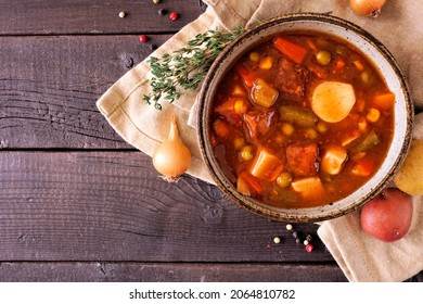 Homemade Beef Vegetable Soup. Top Down View Table Scene On A Dark Wood Background With Copy Space.