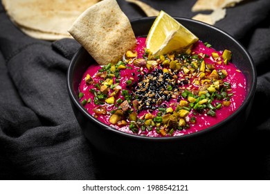 Homemade Beet And Chickpea Hummus With Vegetable Crudités And Unleavened Bread On Dark Background