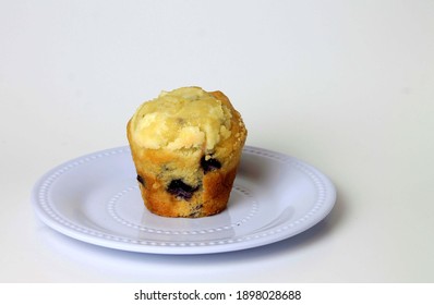 Homemade Blueberry Muffin Resting On White Serving Dish In Studio.