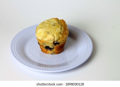 Homemade Blueberry Muffin Resting On A White Serving Dish In The Studio.