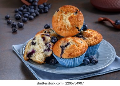 Homemade blueberry muffin split in half with additional muffins on a plate and fresh berries on background. - Powered by Shutterstock