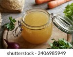 Homemade bone broth in a glass jar, with fresh vegetables