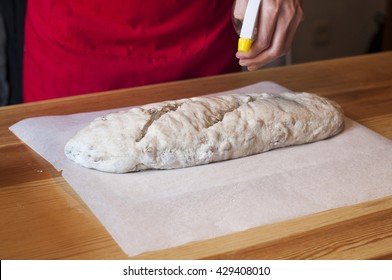 Homemade bread: female hands kneading dough. Spraying water before put in the oven. - Powered by Shutterstock