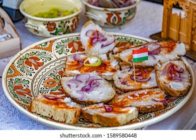 Homemade bread greased with animal fat and sprinkled with paprika and onion on a plate with traditional Hungarian patterns.