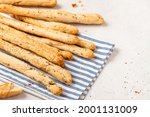 Homemade breadsticks with herbs on a gray concrete background. Grissini - Italian breadsticks