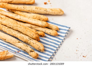 Homemade breadsticks with herbs on a gray concrete background. Grissini - Italian breadsticks