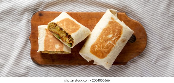 Homemade Breakfast Egg Burrito With Avocado And Bacon On A Rustic Wooden Board, Overhead View. Flat Lay, Top View, From Above.