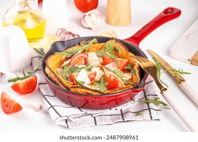 Homemade breakfast savory dutch baby pancake, Portioned frying pan with vegan  savory dutch baby pancake with tomatoes, arugula and cheese - Powered by Shutterstock