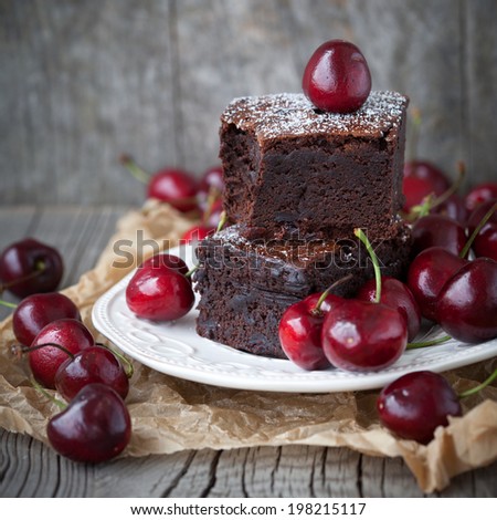 Homemade brownies with fresh berry on old wooden background, selective focus