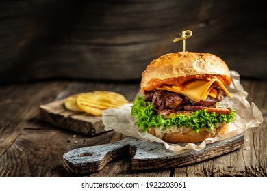 Homemade burger with grilled beef meat, vegetables, sauce on rustic wooden background. fast food and junk food concept.