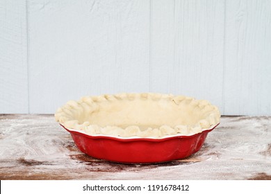 Homemade butter pie crust in pie plate with fluted pinched edge against a rustic wooden background. Crust is empty and ready for baking. - Powered by Shutterstock