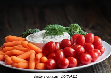 Homemade Buttermilk Ranch Salad Dressing With Dill Served With Fresh Vegetables, Cherry Tomatoes, Baby Carrots And Broccoli, Over A Rustic Wooden Background.