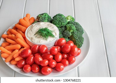 Homemade buttermilk ranch salad dressing with dill served with fresh vegetables, cherry tomatoes, baby carrots and broccoli, over a rustic white wooden table background with room for text. - Powered by Shutterstock