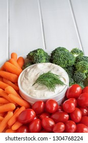 Homemade Buttermilk Ranch Salad Dressing With Dill Served With Fresh Vegetables, Cherry Tomatoes, Baby Carrots And Broccoli, Over A Rustic White Wooden Table Background With Room For Text.