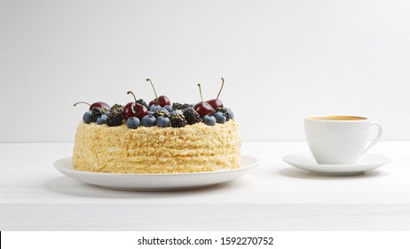 Homemade Cake Decorated With Fresh Berries And Cup Of Coffee On White Wooden Table. Front View. Copy Space.