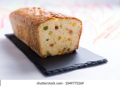 Homemade Candied Fruit Sponge Cake On Blackboard And Colorful Background For Christmas