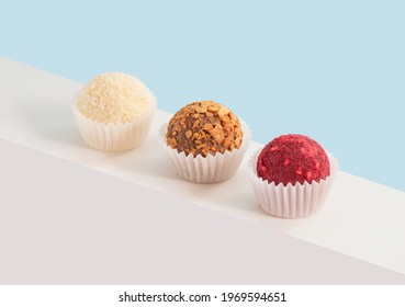 Homemade candies with coconut, dried fruits and nuts on a blue background. Geometric composition with truffles. Isometric view. Copy space.