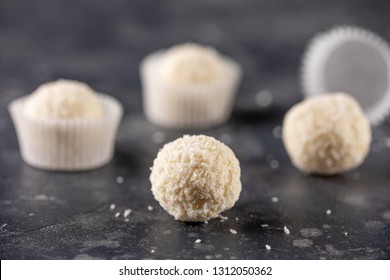 homemade candies with coconut flakes. White chocolate candy coconut truffles on a dark background.