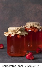 Homemade canned compote with strawberries in two jars on brown background, Vertical format