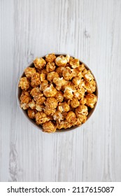 Homemade Caramel Popcorn In A Gray Bowl On A White Wooden Surface, Top View. Flat Lay, Overhead, From Above. Space For Text.