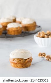 A Homemade Carrot Cake Muffin With Cream Cheese Icing And Others In Behind.