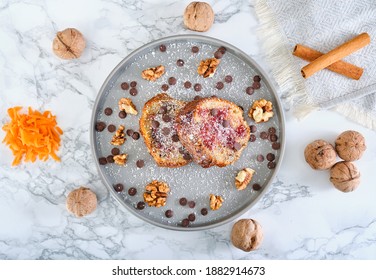 Homemade Carrot Cake With Walnuts And Cinnamon. Overhead Wide Angle Photo With Whole Walnut Chocolate Chips And Cinnamon Rolls In Grey Dish On White Background. 