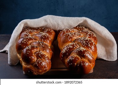 Homemade Challah bread with white cover, Jewish cuisine. Decorated with sesame and poppy seeds. Dark background.