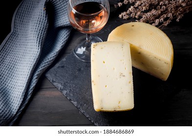 homemade cheese head with lavander on old dark wooden board and glass of wine on table. Fresh dairy product, healthy organic food. Delicious appetizer.