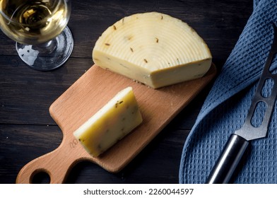 homemade cheese head with lavander on old dark wooden board and glass of wine on table. Fresh dairy product, healthy organic food. Delicious appetizer.