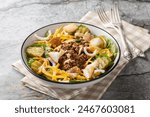 Homemade Cheeseburger Salad with lettuce, ground beef, pickles, cheddar cheese, onions and dressed with spicy sauce closeup on the bowl on the table. Horizontal
