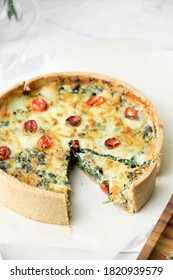 Homemade cheesy spinach quiche for brunch. set on white cafe table background.