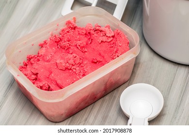 Homemade Cherry Ice Cream In A Plastic Container On The Table Next To An Ice Cream Spoon And An Ice Cream Maker