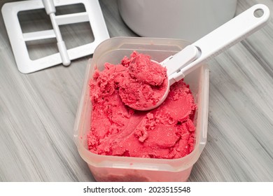 Homemade Cherry Ice Cream In A Plastic Container On The Table With An Ice Cream Spoon And An Ice Cream Maker. High Quality Photo