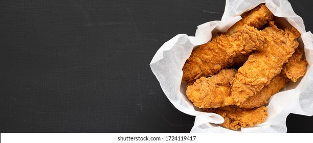 Homemade chicken fingers in paper box on a black background, top view. Flat lay, overhead, from above. Space for text. - Shutterstock ID 1724119417