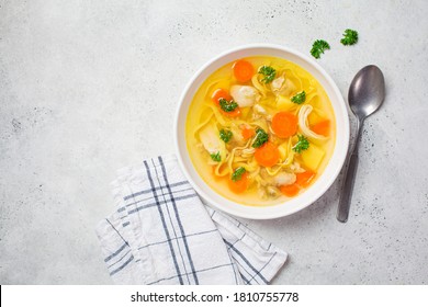 Sopa de pollo casera con fideos y verduras en un cuenco blanco, fondo blanco. Comida saludable y cómoda.