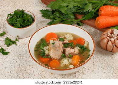Homemade chicken soup with vegetables in a white bowl.Healthy warm comfortable food. - Shutterstock ID 2311629241